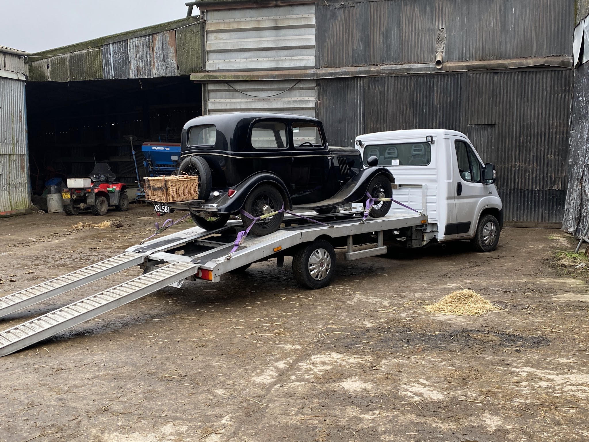 Transporter with ramps lowered and a vintage car secured on the bed